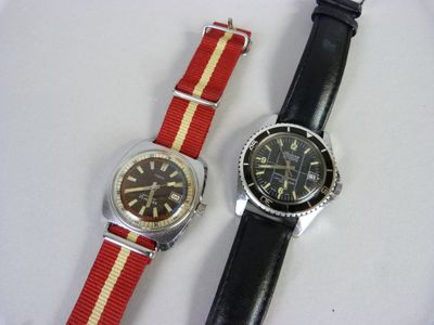 deux montres posées sur une surface blanche ; l'une est rouge et l'autre présente une bande jaune et blanche
