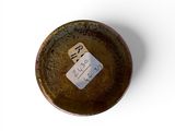 a brown plate with a tag on it on a white surface