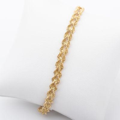 gros plan d'un bracelet en or sur un oreiller blanc