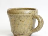 a brown cup with a handle on a white surface