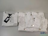 three white t - shirts are sitting on a table next to a pair of scissors
