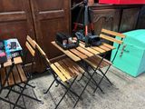trois chaises en bois et une table sur laquelle est posée une caméra