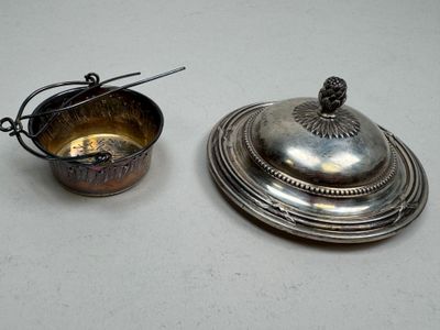 silver plate with a lid and a spoon on a white surface