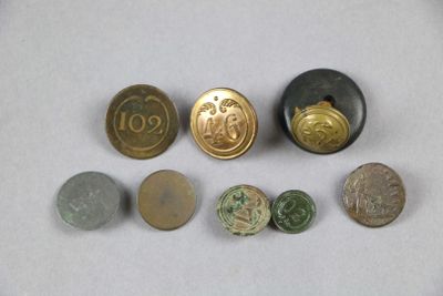 Plusieurs pièces et boutons sont disposés sur une surface blanche.