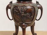 an image of a bronze vase sitting on top of a wooden table