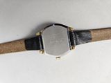 a close up of a watch on a white surface with a black strap