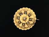 un gros plan d'une broche en or ornée de perles