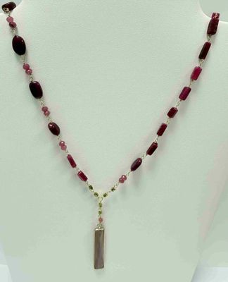 un gros plan d'un collier orné d'une longue perle et d'un pendentif