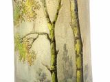 a glass vase with a painting of trees on it