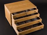 an image of a wooden box with four drawers filled with utensils