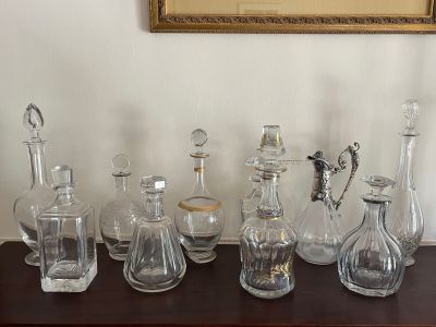a lot of glass bottles on a table with a picture in the background