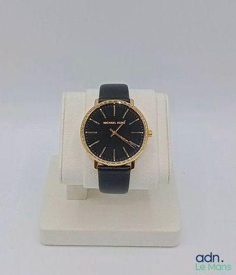 the watch is on display on a white stand with a black strap