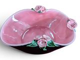 a pink bowl with pink flowers on it on a white surface