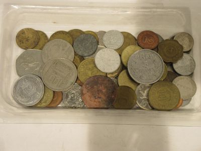 some coins are in a plastic container on a white surface