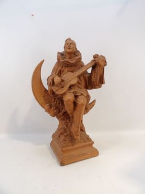 statue d'un homme assis sur un croissant de lune, tenant une harpe