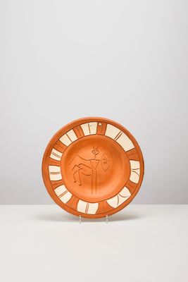 une assiette orange posée sur une table blanche, près d'un mur blanc