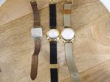 three watches are sitting on a wooden board on a table