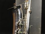 an old silver saxophone sitting on top of a black table