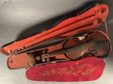 a violin in a case on a table with a red cloth
