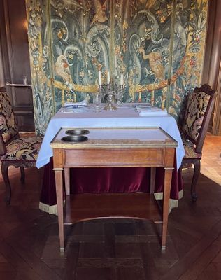 une table et des chaises dans une pièce où est accrochée une tapisserie au mur