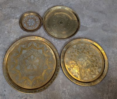 trois plateaux en laiton, dont l'un orné d'un motif floral et l'autre orné d'un motif floral