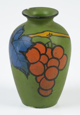 un vase vert sur lequel est peint un bouquet de raisins