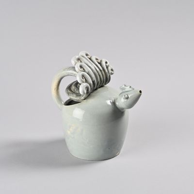 un petit animal en céramique avec un anneau dans la bouche
