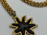 a close up of a gold chain with a black flower on it