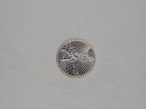 a silver coin with a bird on it on a white surface
