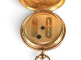 a gold pocket watch that has a key in it