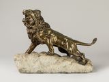une statue en bronze représentant un lion posé sur un rocher, sur fond blanc