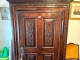 a wooden cabinet with a door and a chair in front of it