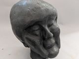 une sculpture représentant une tête d'homme sur une surface blanche