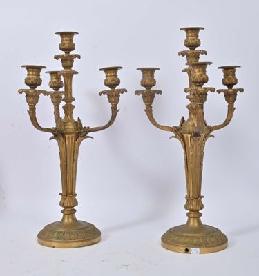 pair of antique brass candelabs on pedestals against a white background
