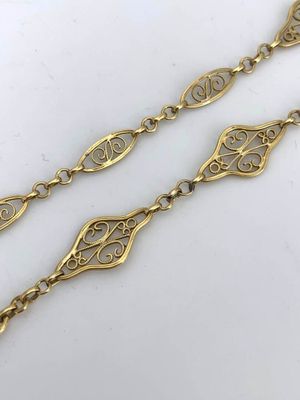a close up of a pair of gold plated bracelets on a white surface
