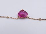 a close up of a pink stone on a gold chain