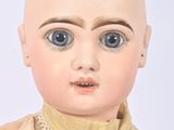 a close up of a doll with a bald head and blue eyes