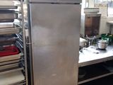 a stainless steel refrigerator in a kitchen with lots of dishes on the counter