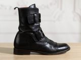 black leather ankle boots with buckles on top of a wooden table