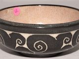 un bol noir et blanc posé sur une table, sur lequel est collé un autocollant rose