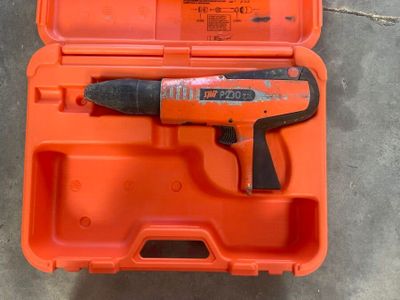 une boîte orange posée par terre, contenant un marteau