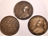 trois médaillons en bronze représentant un homme et une femme sur un fond blanc