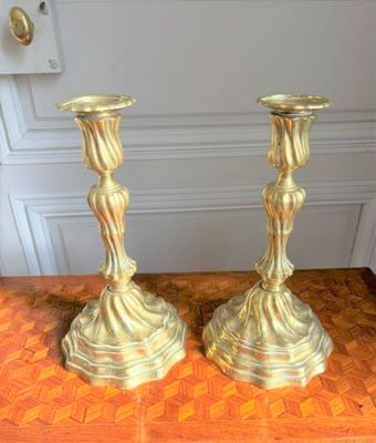 two gold candlesticks sitting on a wooden table