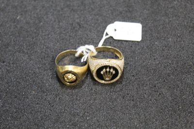 two gold rings with black stones on them on a black surface
