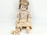 a doll that is sitting on the ground with a hat on