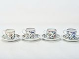 four cups and saucers are lined up on a white surface