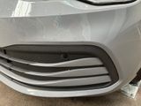 the front of a car with a denting dent on it ' s bumper
