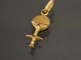 a close up of a gold plated key charm on a black surface