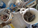several buckets filled with assorted items sitting on a tiled floor