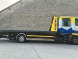 a yellow and blue tow truck parked in front of a building